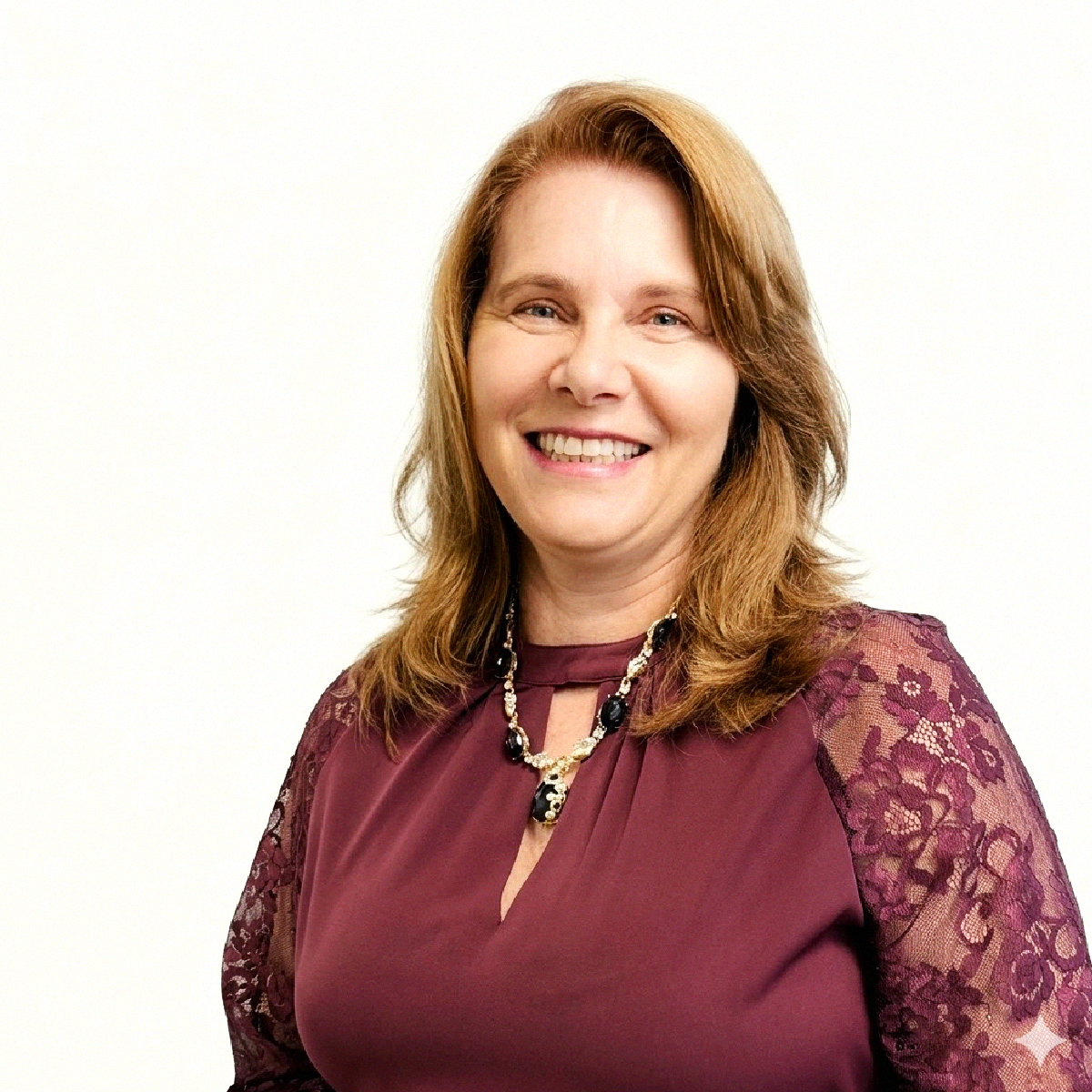Ana Cristina Borges sorrindo, usando blusa vinho com detalhes em renda e colar de pedras pretas.