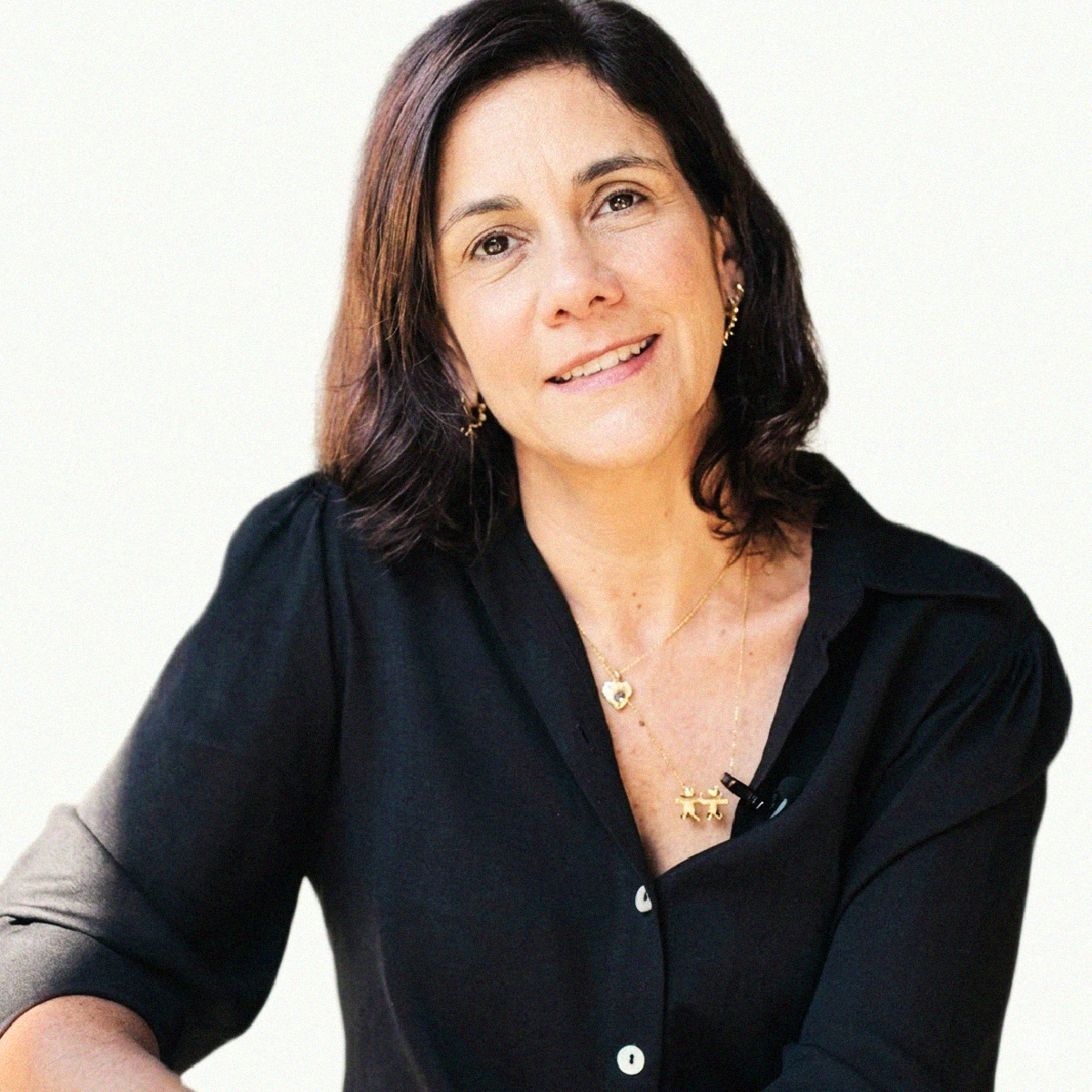 Retrato profissional da Profa. Karima Fernanda Rosa Simão Martins sorrindo, de óculos, cabelos castanhos claros ondulados e blusa de tom azul-petróleo, braços cruzados.